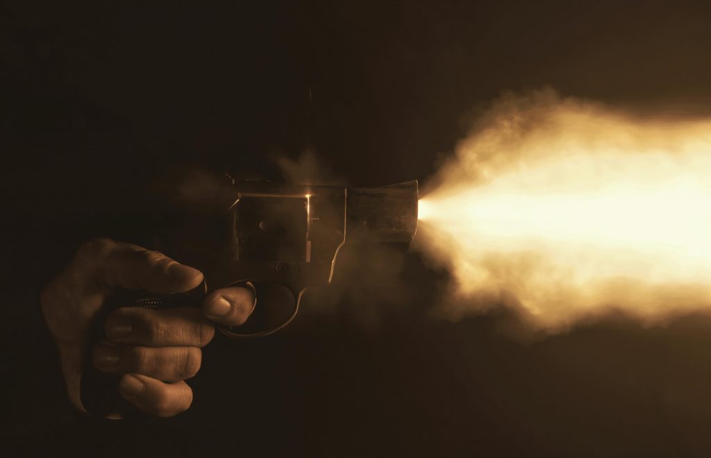 Mano sosteniendo un arma de fuego durante un disparo, imagen simbólica del miedo a la violencia urbana y la inseguridad
